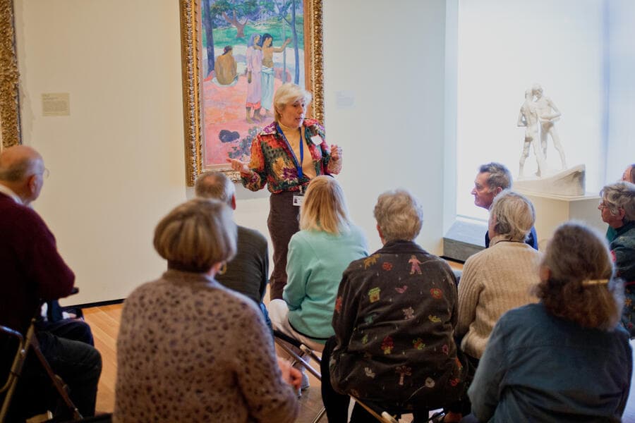 Docent speaking to visitors in front of a Gauguin painting.