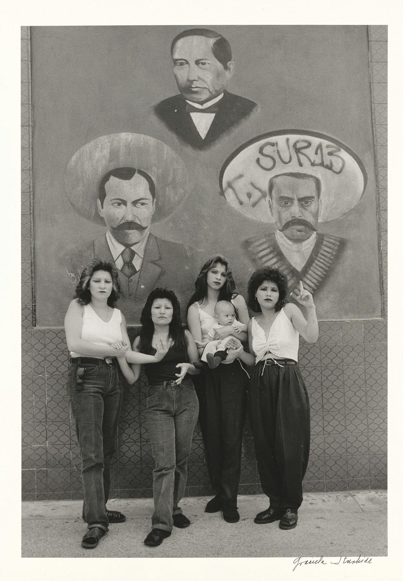 four women and baby standing in front of mural