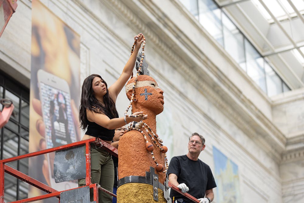 Woman putting necklace on giant statue