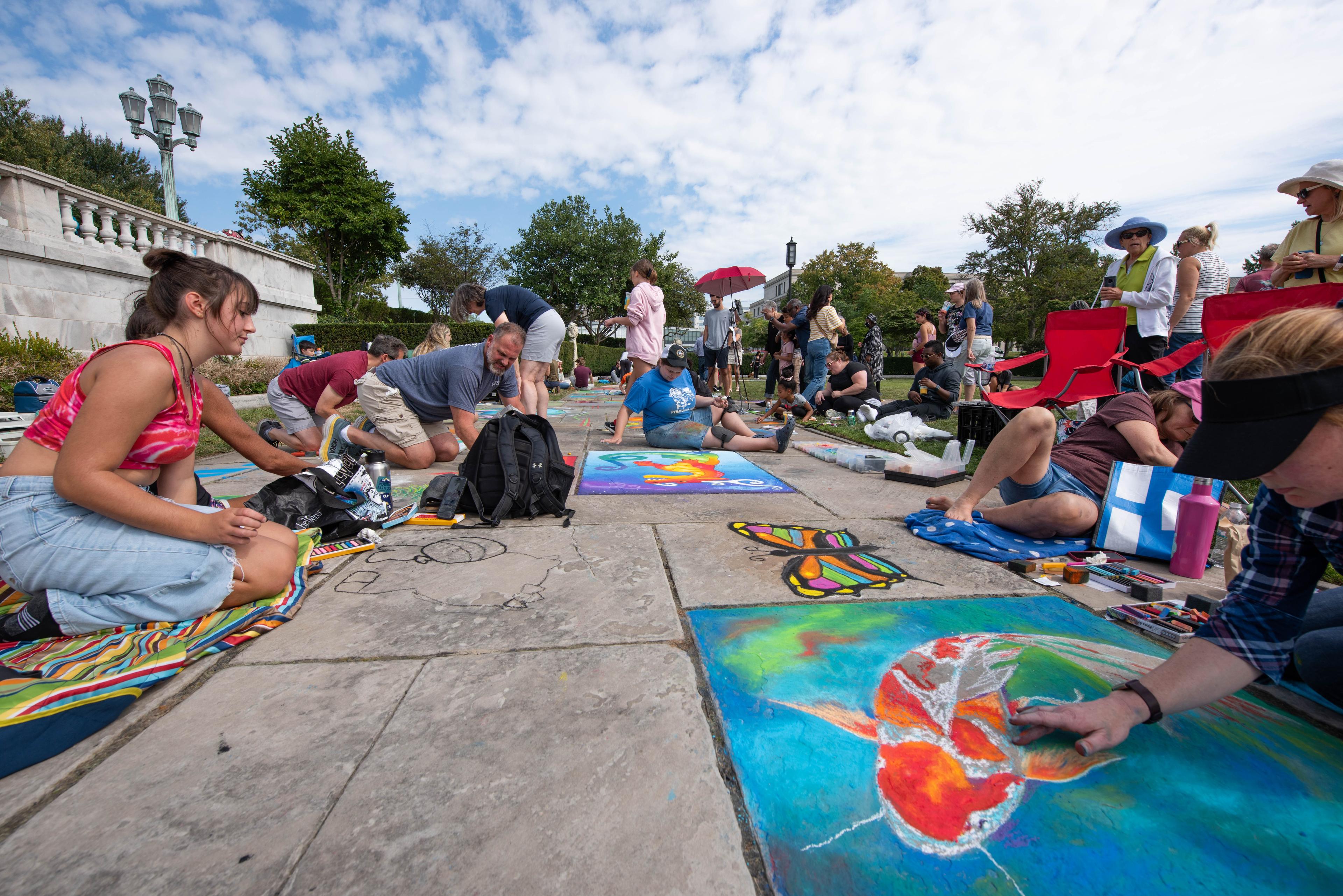 People creating chalk art on the stairs of the museum grounds