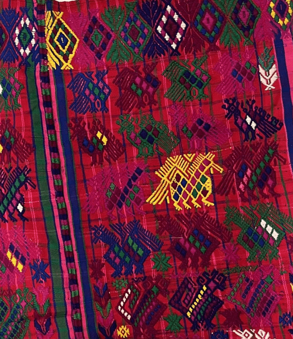 Detail of a colorful woven textile with geometric cultural animal symbols.