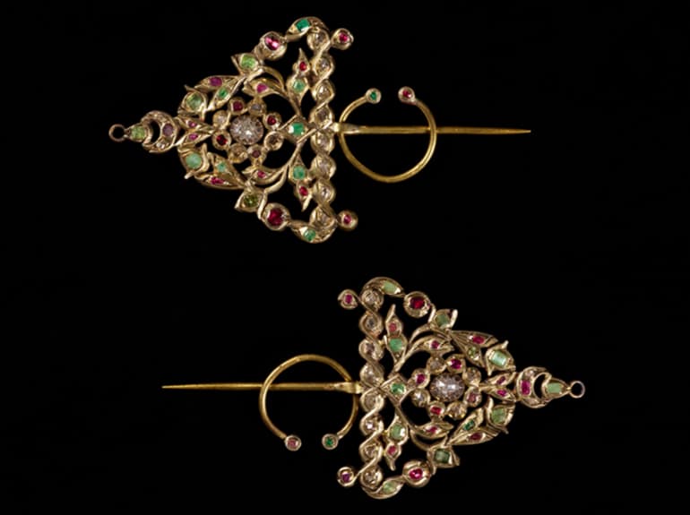 Two triangle-shaped gold bejeweled earrings, one above the other pointing in opposite directions