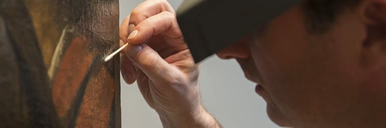 Conservator of Paintings Dean Yoder cleans The Crucifixion of Saint Andrew by Caravaggio. Photograph by Howard Agriesti
