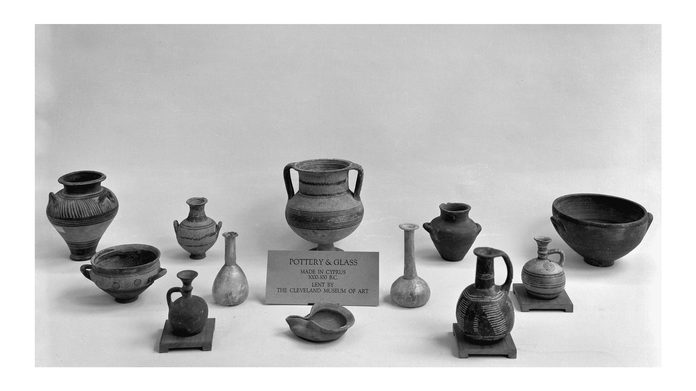 A black and white image of pottery and glass vases against a white background.